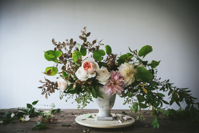 Composition of flowers and plants in vintage vase on board