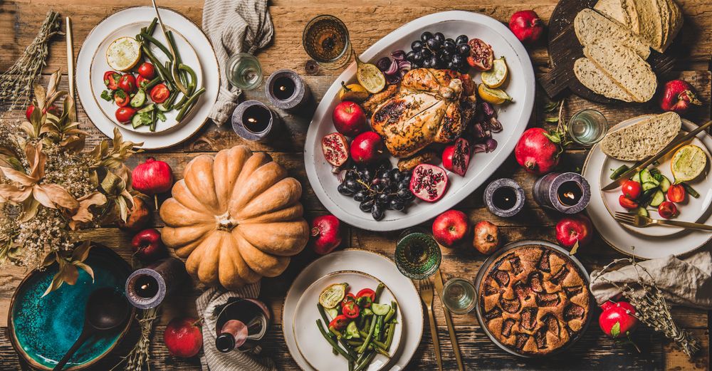 Autumnal table setting with squash, candles, roast chicken, pomegranate, fig pie and rose champagne