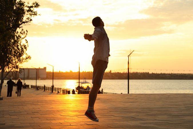 Photo of a young man in a jump. Happy man. Amazing sunset