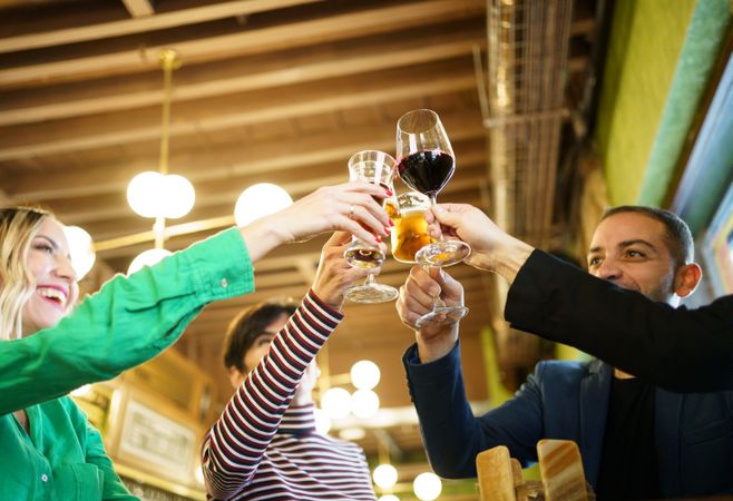 Group of friends celebrating beer and wine in bar