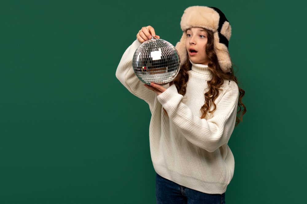Surprised girl in winter hat looking at disco ball.