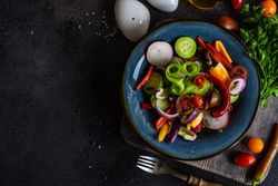 Top view of colorful healthy raw vegetable salad served on blue plate