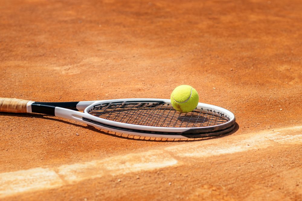 Tennis racket and ball on a dirt court