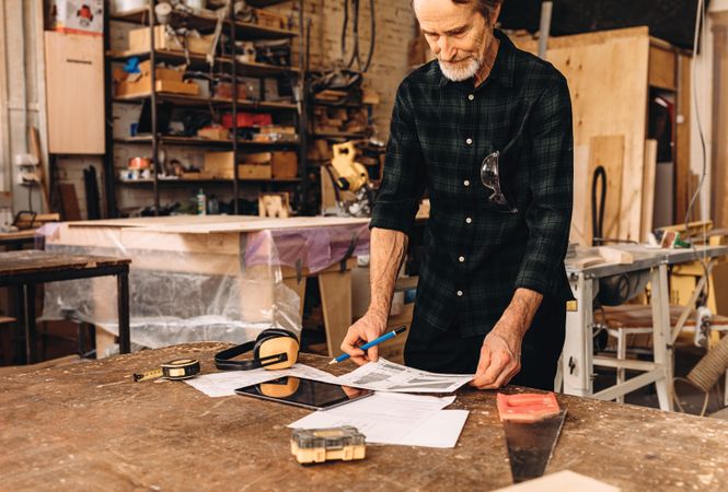 Older man with design plans in his woodwork shop