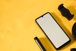 Mock up phone on yellow table with accessories, shadow and space for text