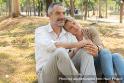 Calm mature woman leaning her head on man’s shoulder while sitting in park 5kAdPb