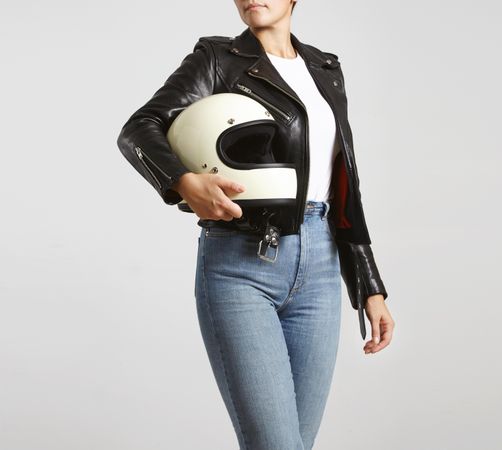 Woman in dark leather jacket with light t-shirt posing with motorcycle helmet