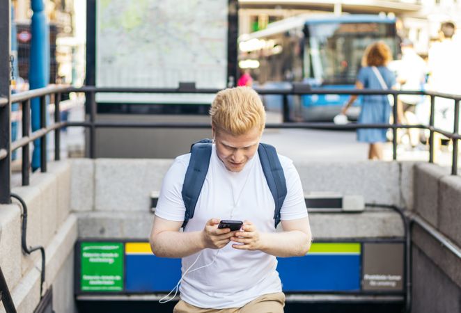 Latino man with albinism using smartphone in the city