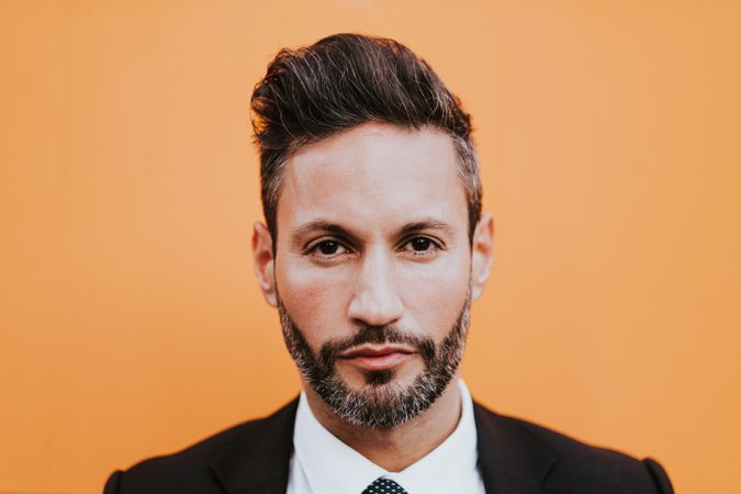 Adult stylish man in costume near orange wall