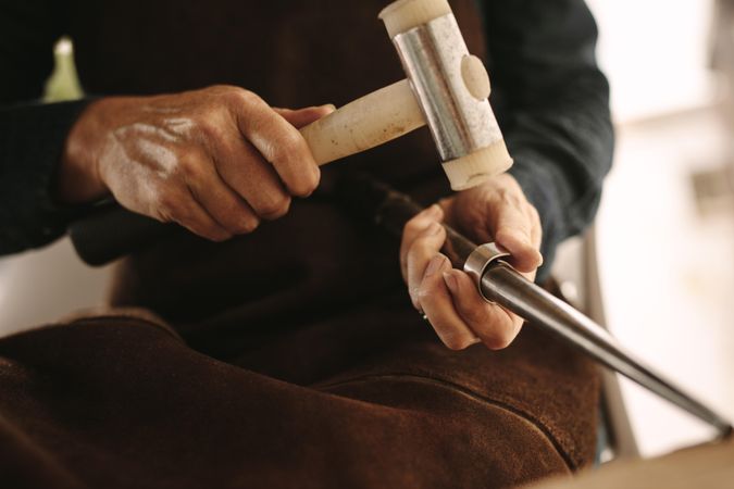 Jeweler working with the hammer on silver ring in her workshop