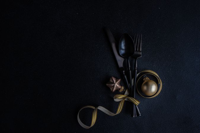 Dark cutlery on dark background tied with festive gold ribbon