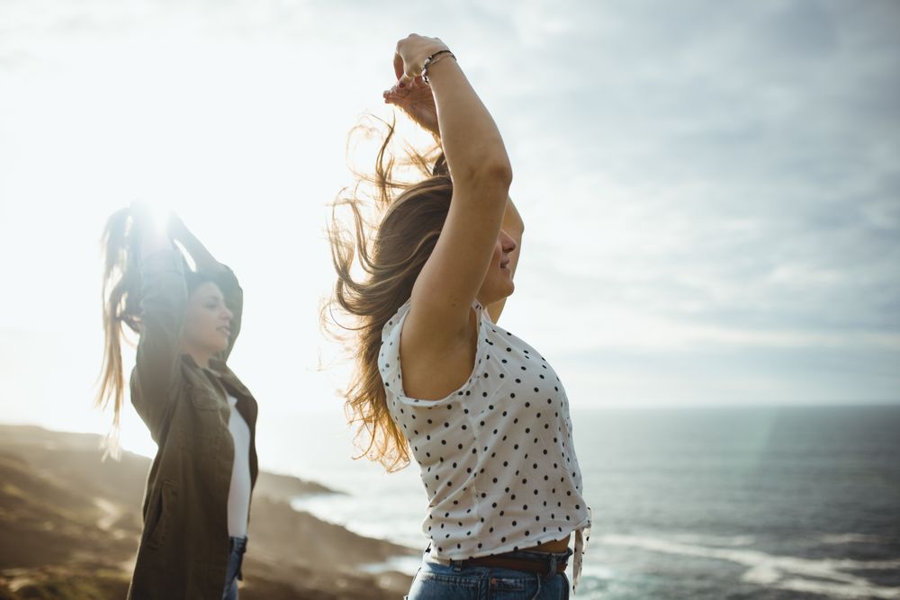 Happy female travelers enjoying freedom at seaside