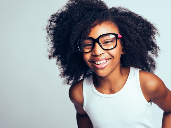 Studio portrait of laughing confident girl wearing large glasses