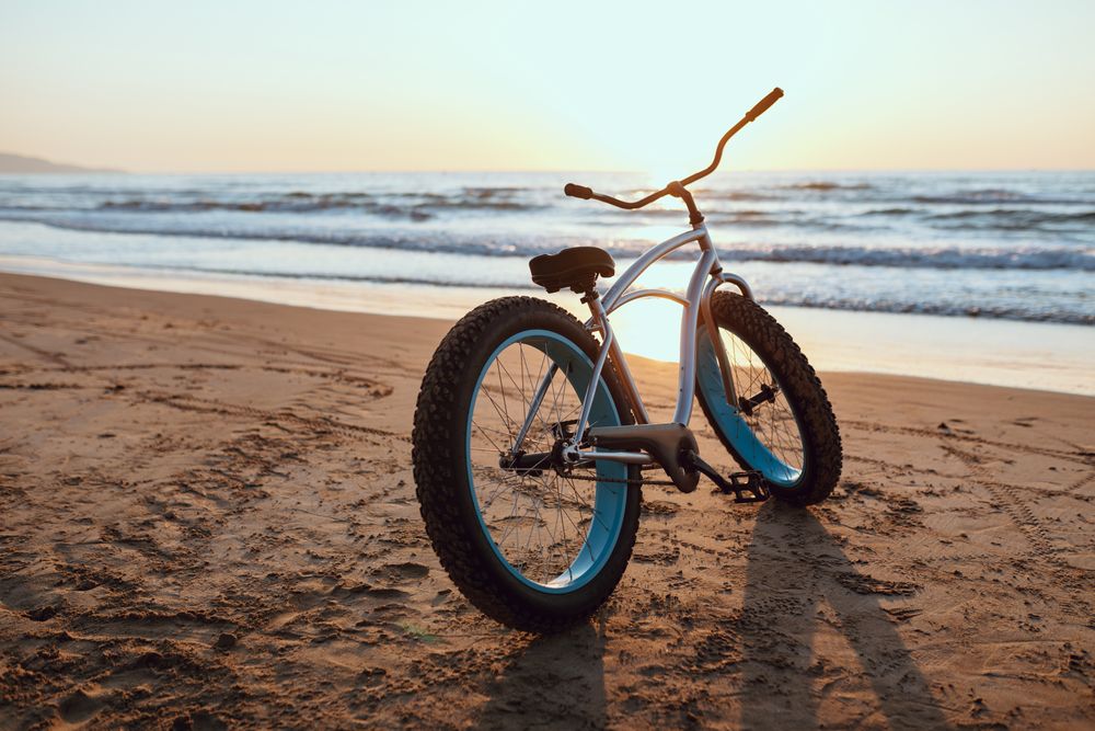 Modern fat bicycle parked at beach on sunset