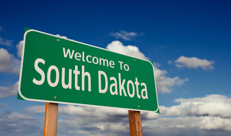 Welcome To South Dakota Green Road Sign Over Blue Sky with Some Clouds.