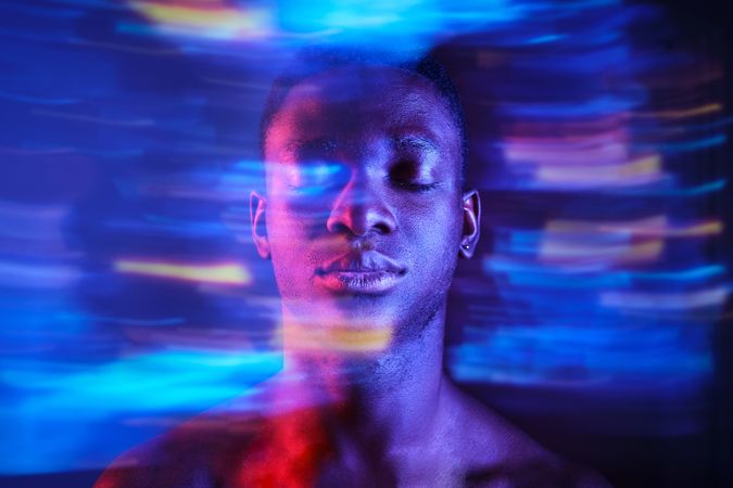 Black man with eyes closed in blurred blue lights