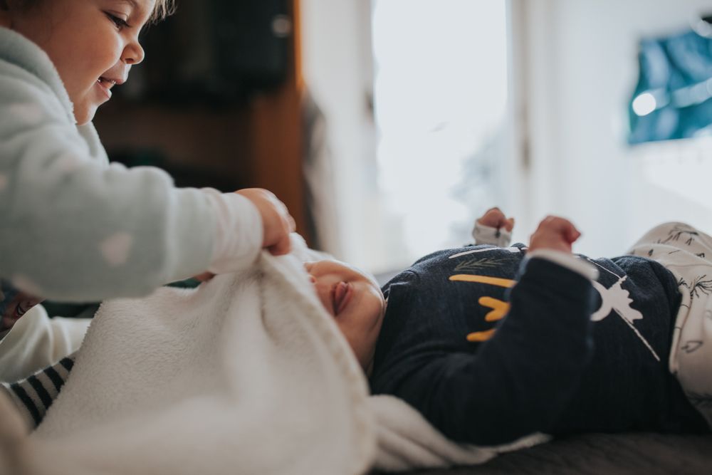Toddler plays with newborn