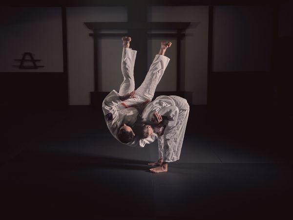 Male and female judo practitioners performing throw exercise in studio