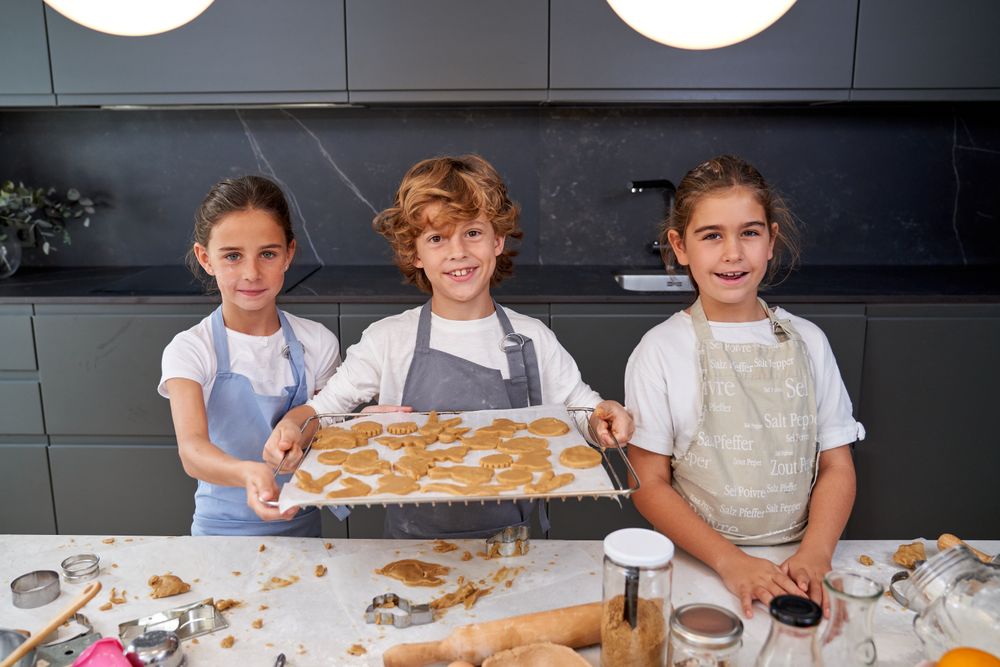 Cheerful children with baking pan of raw cookies
