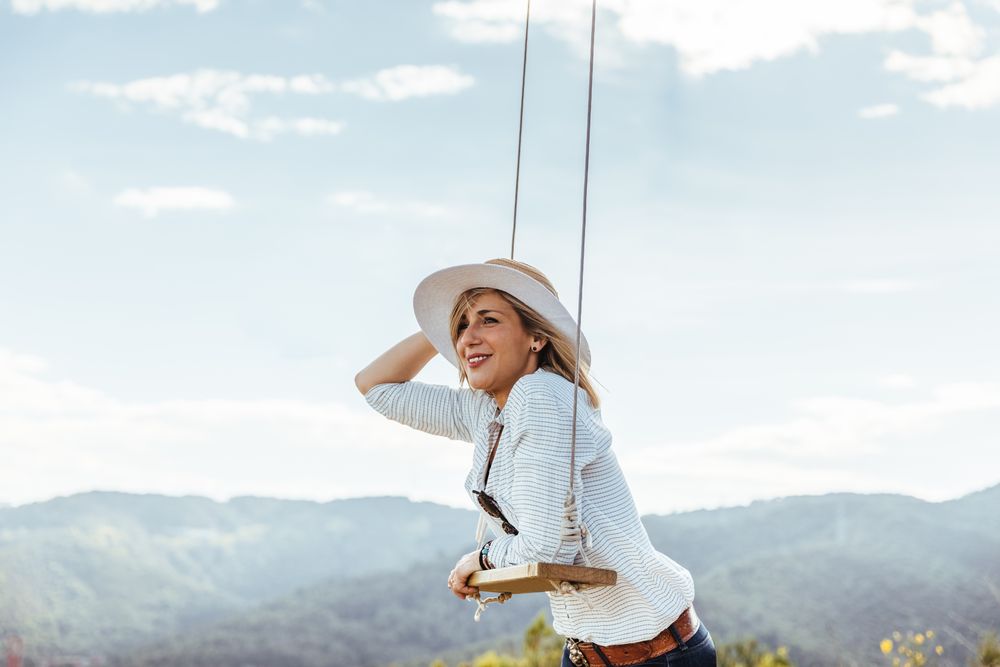 Happy woman with hat next to a swing