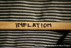Close up of the word “inflation” written on wooden stick laying on striped fabric 5olG84