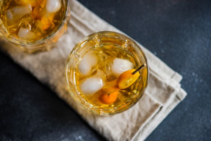 Whisky on ice with slice of kumquat fruit