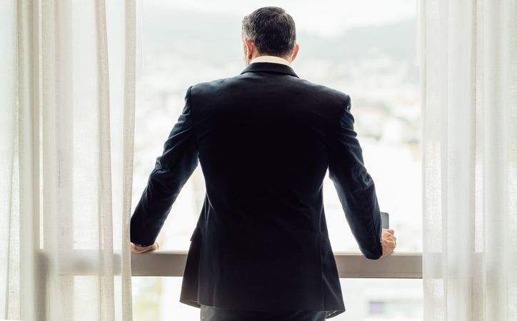 Businessman standing by hotel room window