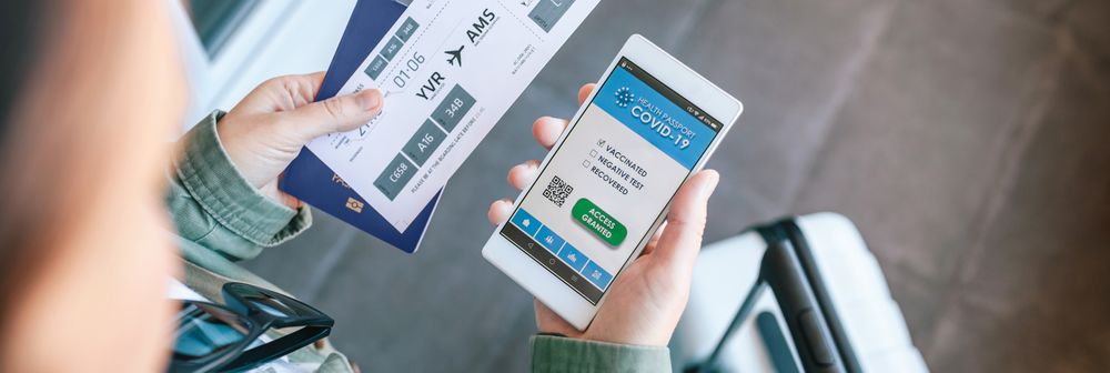 Unrecognizable woman holding cell phone with covid passport and
