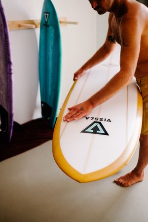 Man preparing surfboard at home before heading to the beach