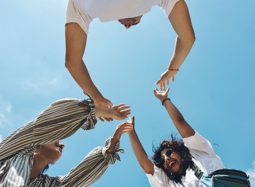 Group of friends embraced and putting their hands together.