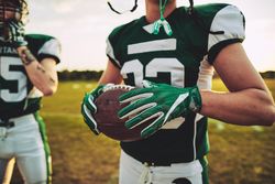 Man holding football on the field with his teammates