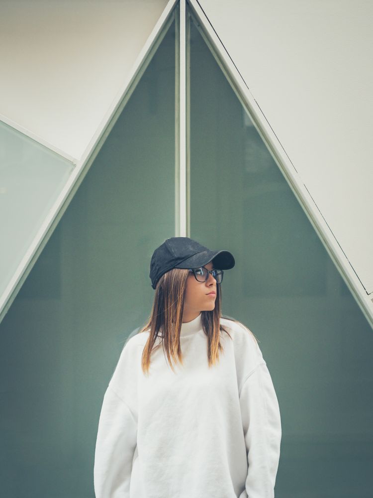 Young woman with glasses standing against wall