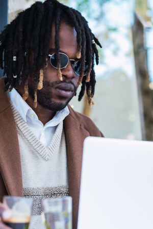 Serious Black man with espresso and glass of water in cafe