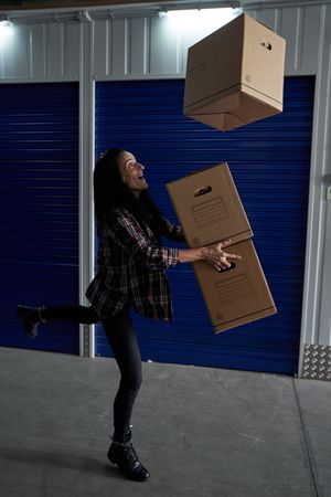Cheerful woman tossing up carton boxes