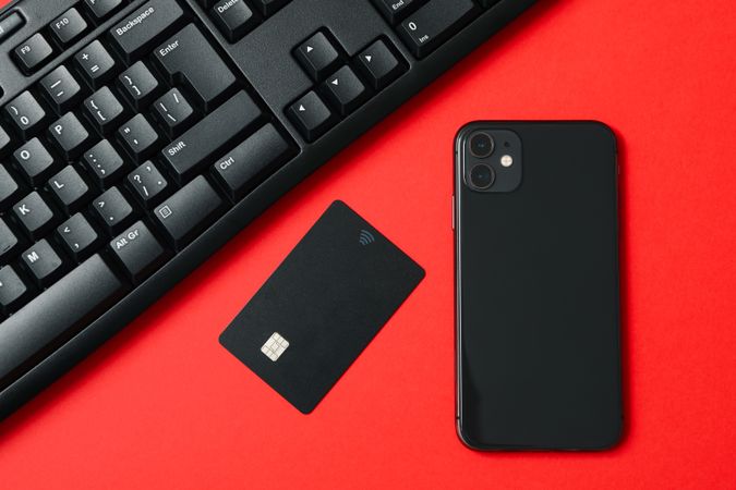 Phone, keyboard and card on red background