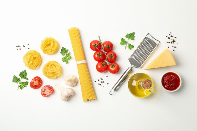 Composition with pasta and ingredients for cooking on plain background, top view