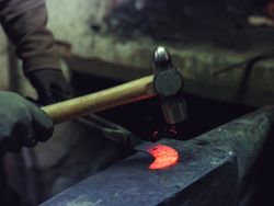 Crop farrier forging iron in workshop