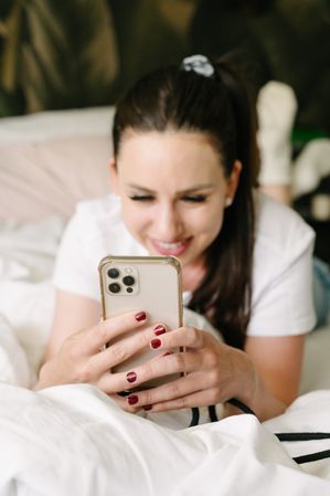 Positive woman using smartphone on bed