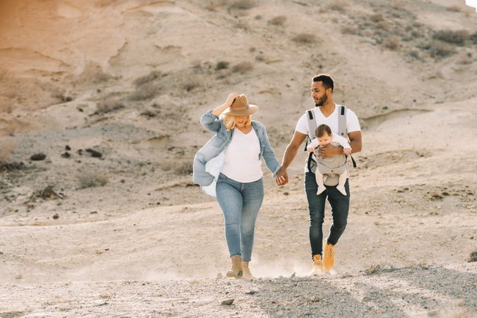 Diverse parents dancing while walking with baby