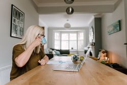 Mature woman with grey hair working from home in kitchen