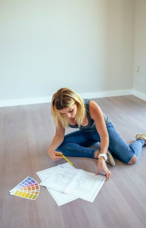 Woman looking house plans over the floor