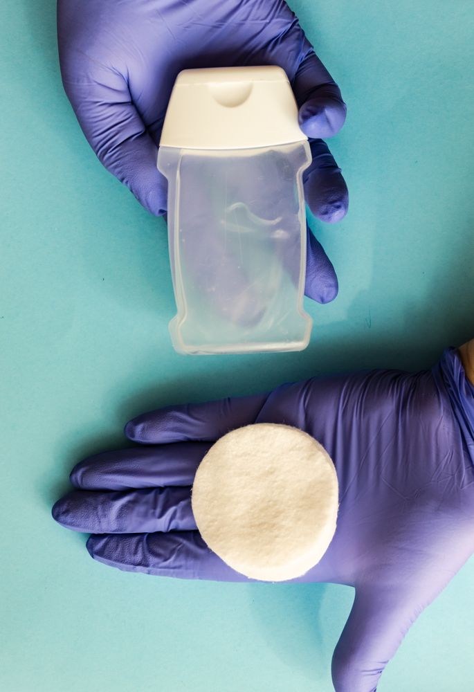 Covid-19 virus concept of looking down at hands in latex gloves with cotton swabs and anti bacterial soap