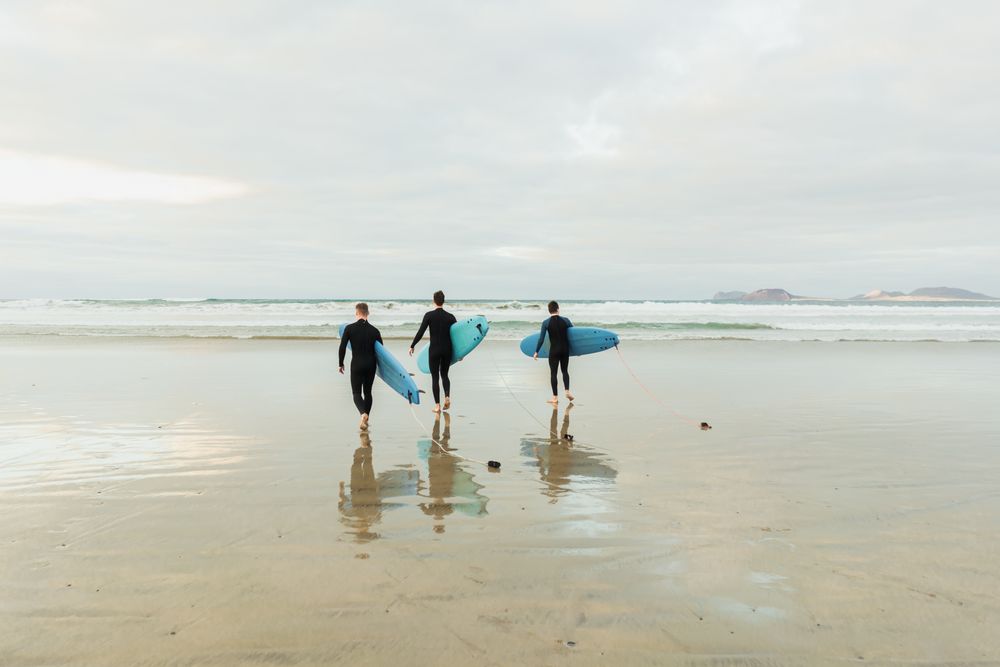 People with surfboard walking near sea