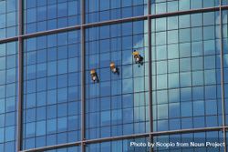 Three people cleaning windows of skyscraper 4dkZD5