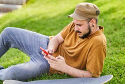 Relaxed man lying on the grass using the phone