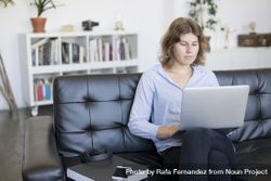 Woman sitting on a sofa at home working on a laptop 4d8a6D