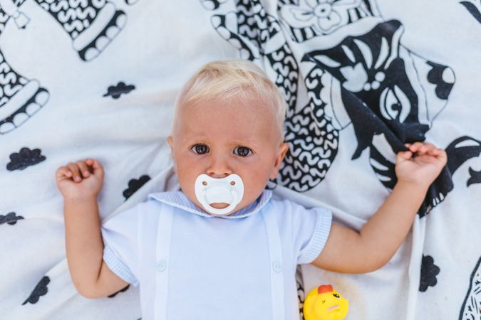 Top view of a blonde baby with pacifier