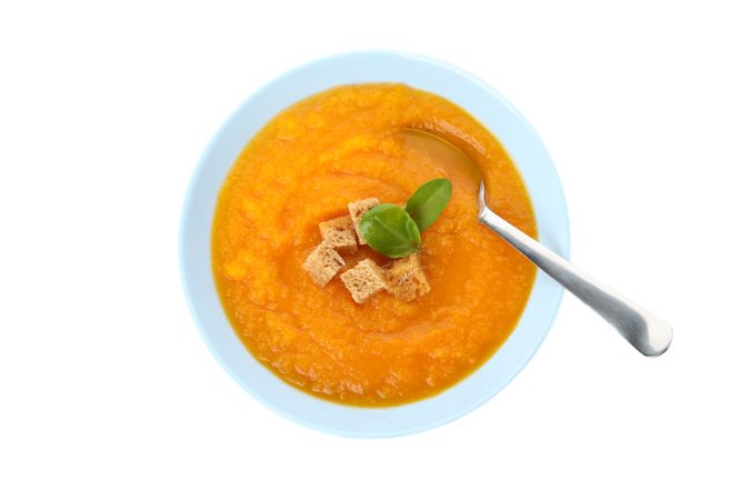 Top view of pumpkin soup with croutons and spoon