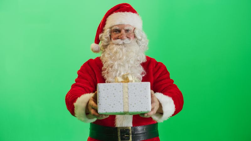Studio Shot Isolated Mockup Template: Jolly Santa Claus Offering Beautifully Wrapped Gift To Children On Green Screen Chromakey Background. Concept Of Christmas, Holidays, New Year, Celebration