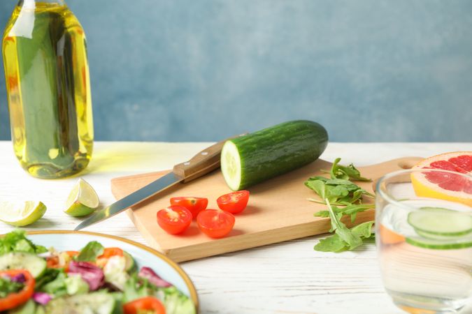 Salad ingredients, knife and oil on wooden background, space for text